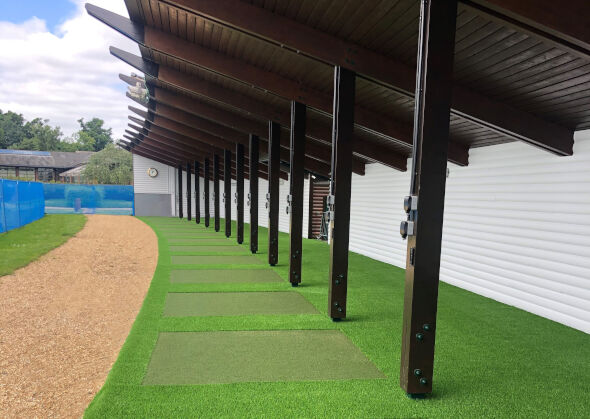 Fresno Covered outdoor tee line with light green synthetic grass boxes inside a dark green synthetic grass strip